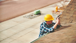 man with yellow hard hat inspecting roof